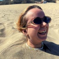 Fundraiserin steckt mit dem Körper im Sand und lacht