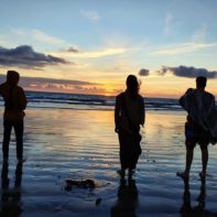 Drei Fundraiser betrachten den Sonnenuntergang am Strand