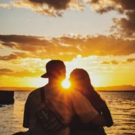 Zwei umarmende Personen genießen den Sonnenuntergang am Strand