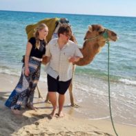 Zwei Fundraiser vor einem Kamel am Strand