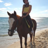 Eine Fundraiserin sitzt auf einem Pferd am Strand