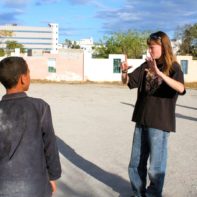 Eine Fundraiserin verständigt sich mit Handzeichen mit einem Jungen aus dem SOS-Kinderdorf
