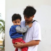 Ein talk2move Fundraiser hält einen kleinen Jungen aus dem SOS Kinderdorf auf dem Arm