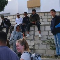 Eine Gruppe von tunesichen Kindern sitzen auf einer Mauer