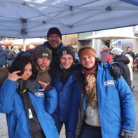 Fünf Fundraiser in blauen Plan-International Jacken stehen in einer belebten Fußgängerzone
