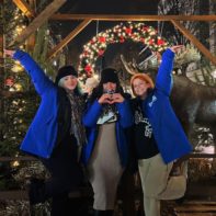 Drei Fundraiser in blauen Plan-Jakcen stehen vor einem Weihnachtsmarkt