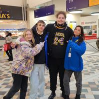 Vier Fundraiser in blauen Fleecejacken stehen in einem Bahnhof