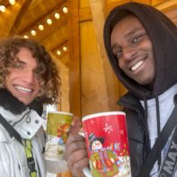 Zwei Fundriaser halten Tassen auf einem Weihnachtsmarkt in der Hand