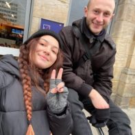 Zwei Fundraiser sitzen vor einem Bahnhof