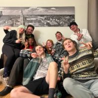 Acht Fundraiser sitzen gemeinsam auf dem Sofa und machen ein "Peace-Zeichen" mit ihren Händen