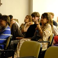 Eine Gruppe von mehreren Personen sitzen auf Stühlen und hören gespannt einem Vortrag zu.
