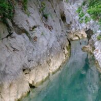 Ein schmaler türkisfarbener Fluss umgeben von steilen Felswänden